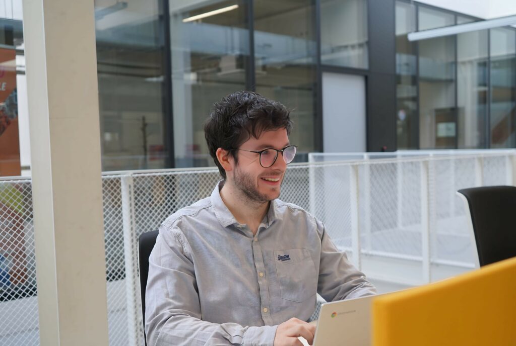 Assistant à distance assis en extérieur, travaillant depuis un espace moderne.